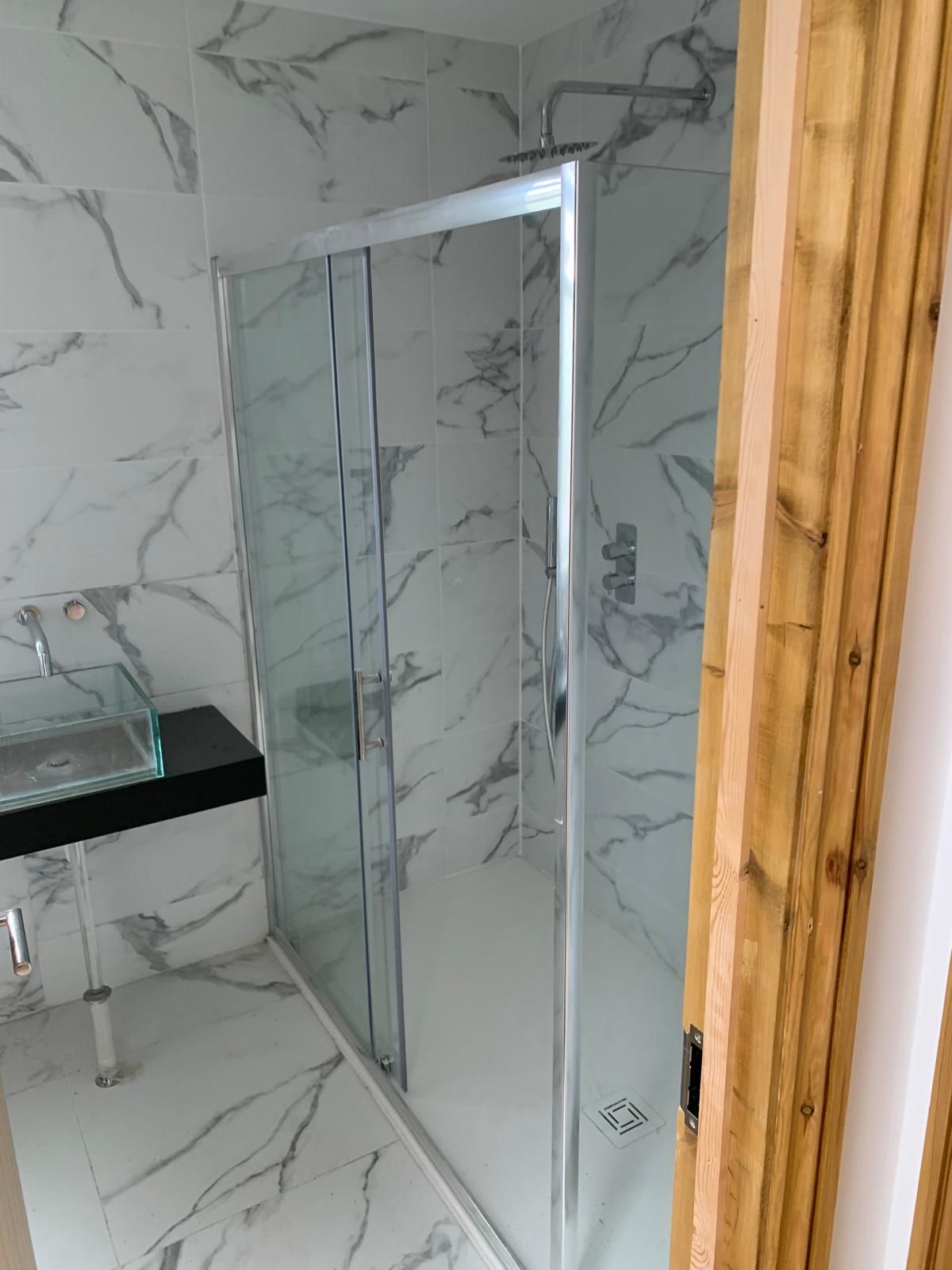 Completed marble effect tiled shower room with glass enclosure